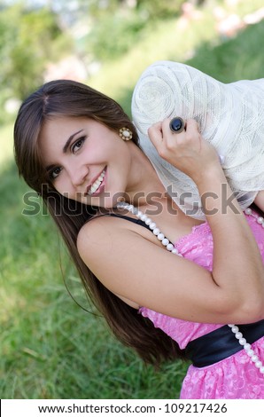 beautiful young woman in hat enjoys summer in the park