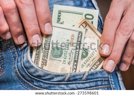 hand holding dollar cash taking out of jeans pocket