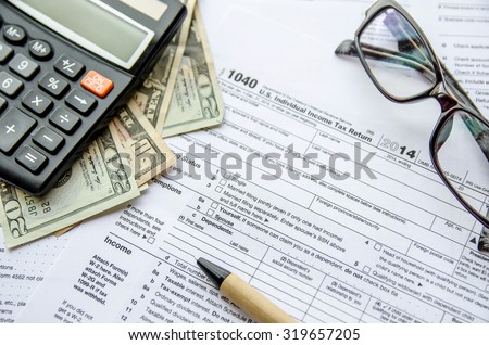 federal income tax return IRS 1040 documents with pen, calculator, dollars