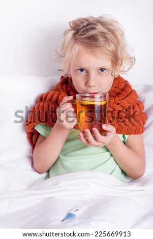 Cute blond girl lying in bed with cup of tea
