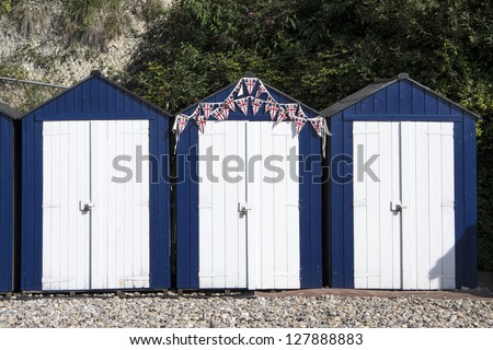Three Blue and White Beach Huts at Beer, Devon, UK.