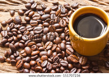 Cup of black coffee and coffee beans on  wooden background.
