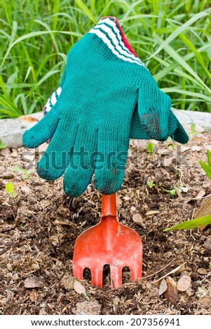 Red fork and green gloves in the garden