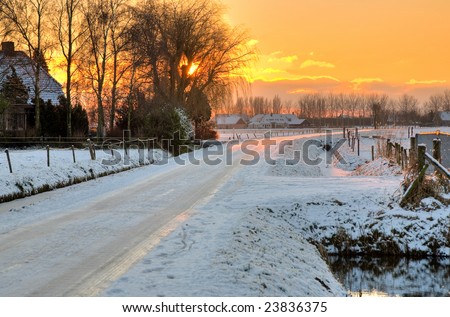 Road covered with snow and ice along farm houses
