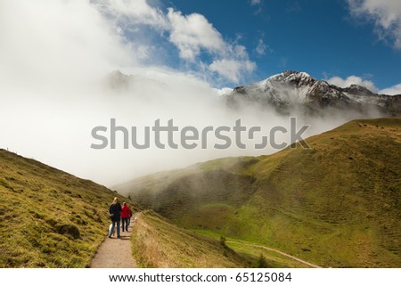 Mountain range peaking through clouds with walking tourists