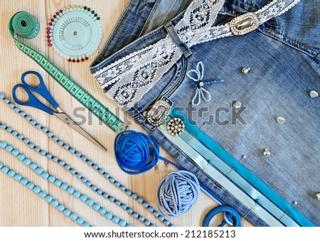 Jeans decorated with ribbons and lace by hand on a wooden background