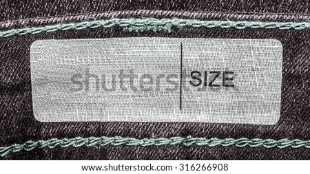 white  textile label on brown denim background, size