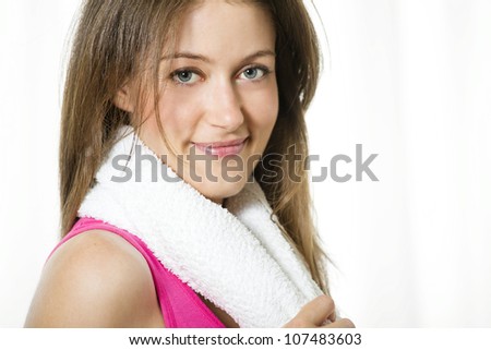 Happy young fitness woman holding towel around her neck