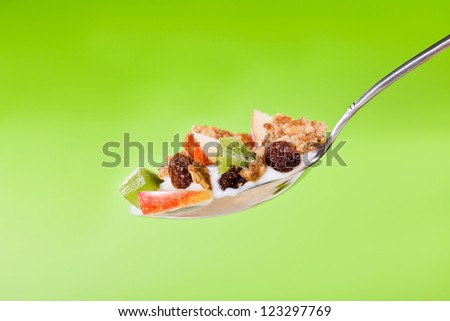 Photograph of a spoon of healthy fruit yogurt with cereals