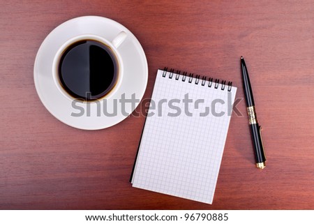 Cup of coffee, notebook and pen on table