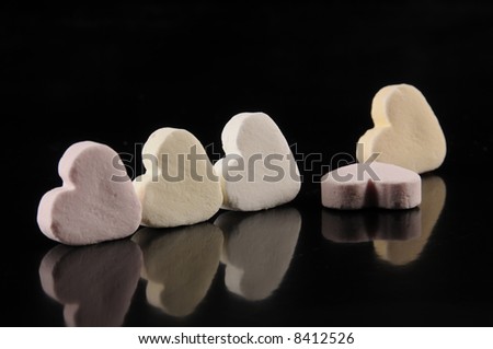 heart shape candy on a row against black background with reflection