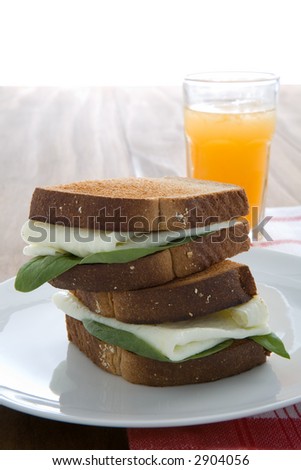 Egg white sandwich on wheat toast, green spinach, and fresh squeezed orange juice