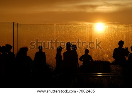a couple people enjoing the sunset after the rain on the top of a building