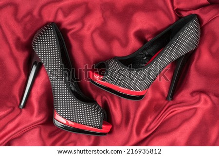 High-heeled shoes lying on red fabric, can use as background