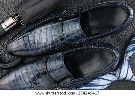 Classic blue men\'s shoes, tie, umbrella on the black leather, can be used as background