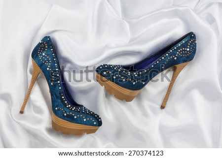 High-heeled shoes  lying on white  fabric, can use as background