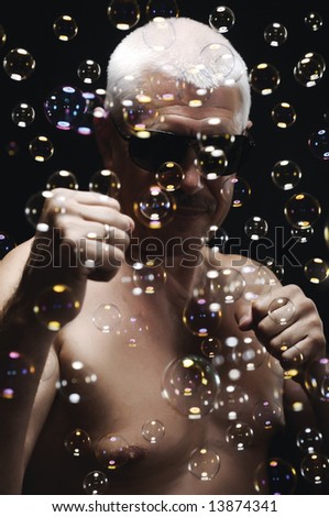 Senor man in sunglasses and soap bubbles on black background