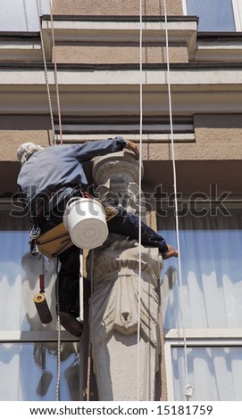 Washerman hangs on the rope and clean the window