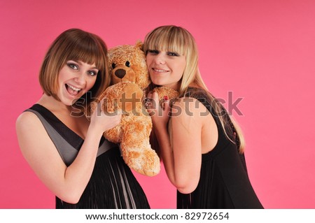 Two bolnde girls with bear on pink background