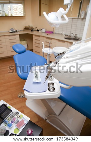 A shot of a dental office with blue chair and dental instruments at the front