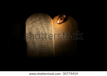 Biblical Ten Commandments inscribed on stone tablets in the Paleo-hebrew script with ancient oil lamp