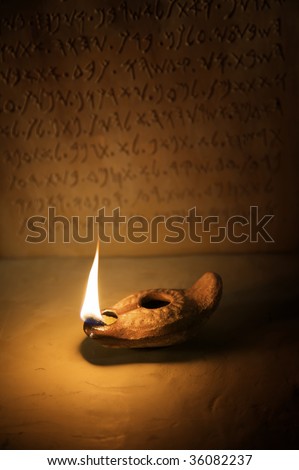 A burning ancient oil lamp with an inscription in the background of the ten commandments written in the Paleo-hebrew script.