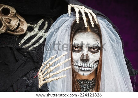 Young woman a bride in a veil day of the dead mask skull face art and skeleton. Halloween face art.