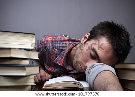 stock photo : Exhausted young man sleeping with bunch of books around him