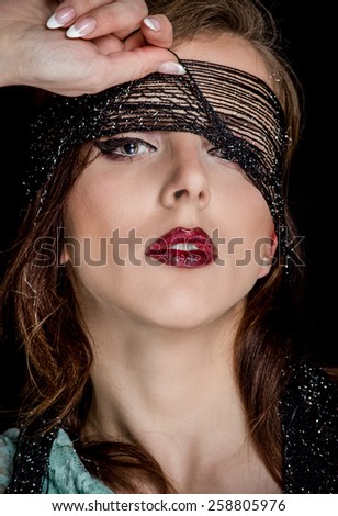 Close up Gorgeous Young Woman with Makeup, Pulling up the Black Net on her Face While Looking at the Camera Sensually, on a Black Background