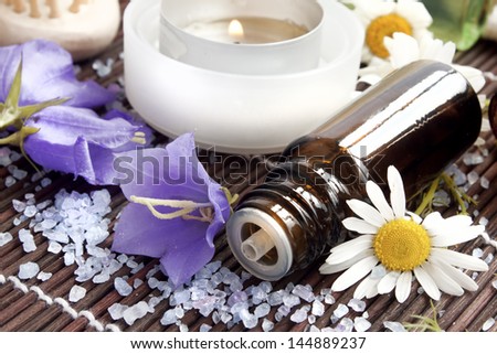 bottle of flower essence,spa candle,sea salt and flowers for spa treatments