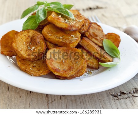 Round spicy baked potatoes with condiments and basil leaves
