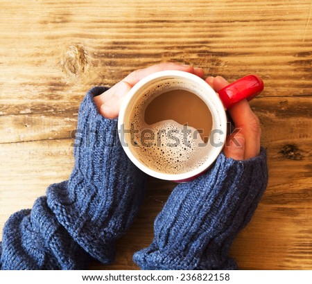 Warm Hands Holding Chocolate Cup on Wooden Background