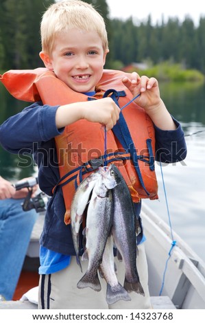 Little boy holding four trout with a big toothless smile