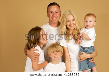 Portrait of a beautiful loving family of five all snuggled together in white tee shirts and jeans