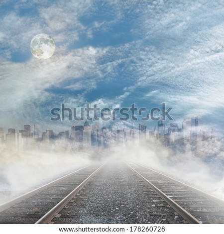 Rails to foggy city skyline with cloudy sky and full moon.