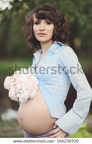 Happy young pregnant woman touching her belly