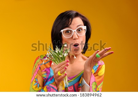 Pretty girl in glasses and snowdrops in the hands over yellow background