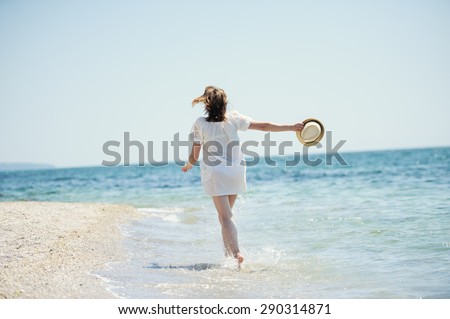happy girl in white dress  running on the sea beach