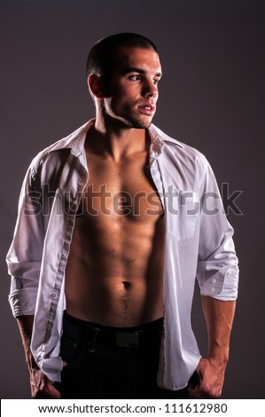Attractive young man with white shirt and strong abs, staring over shoulder