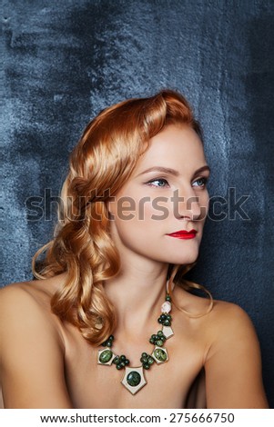 Young beautiful red-haired girl with chiseled cheekbones in designer jewelry