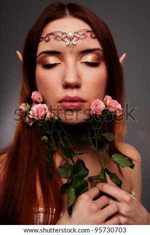 Girl elf with a tiara on her head and closed eyes leaning against a face a bouquet of roses beige
