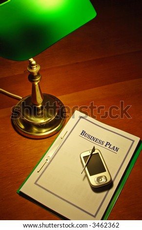 PDA and Business Plan on top of a wooden office desk.