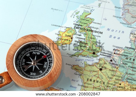 Compass on a map pointing at United Kingdom and Ireland, planning a travel destination