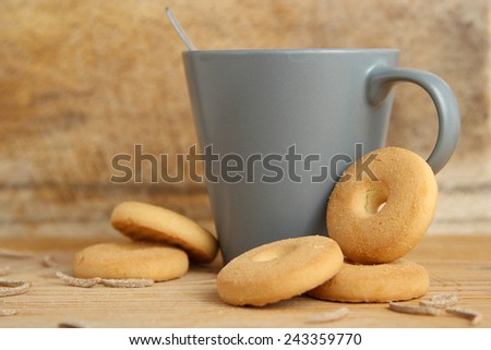 A cup of milk with round cookies and bran sticks on a wooden table