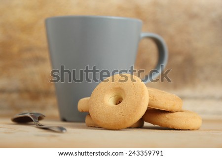 A pile of round biscuits near a mug of milk on a wooden background