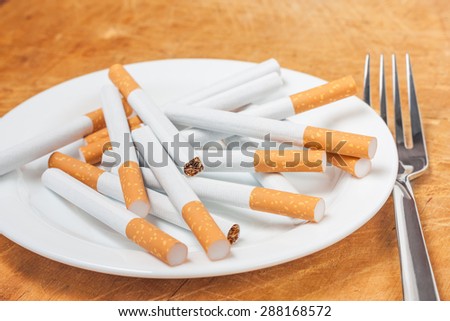 A pile of cigarettes on a plate with fork. Quit smoking
