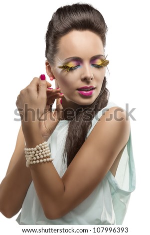 beautiful girl with long hair and feathered makeup, her face is turned at left, she has closed eyes and her hands are near the face