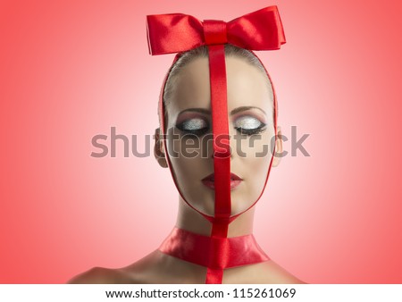 pretty girl with red ribbon on the face and bow on the head, she is in front of the camera and her eyes are closed
