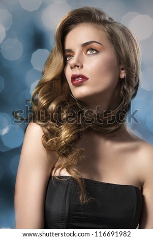beautiful woman with long wavy hair and dark dress, her face is turned at right and she looks up