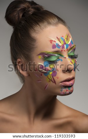pretty girl with abstract make-up on the face, she is turned at left and looks down